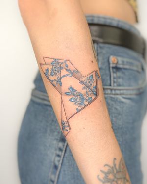 Illustrative tattoo by Bradley Mollett featuring a porcelain-like blue bird in origami style