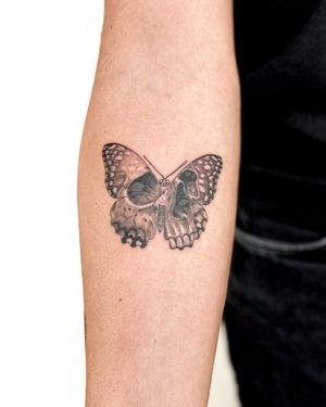 Unique black and gray illustrative tattoo combining a butterfly and skull design by talented artist Bradley Mollett.