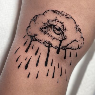 Illustrative tattoo by Andrew Garinther featuring a mystical eye design with woodcut and etch elements, set against a backdrop of swirling medieval clouds.