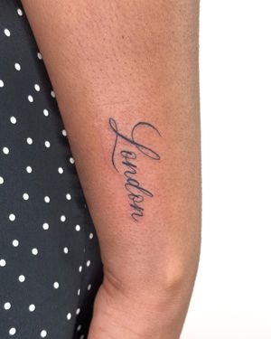 Small lettering tattoo featuring a personalized name, expertly executed by tattoo artist Bradley Mollett.