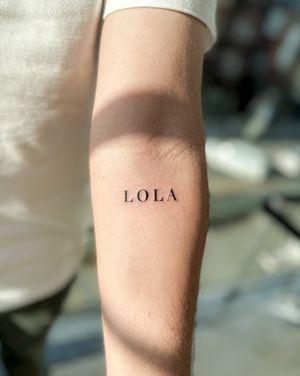 Get a beautifully designed small lettering tattoo of your name by talented artist Bradley Mollett. Perfect for subtle and meaningful personal expression.