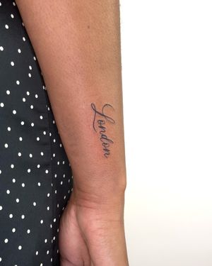 Get a minimalist touch with small lettering tattooed by the talented Bradley Mollett. Perfect for a subtle and personal statement.
