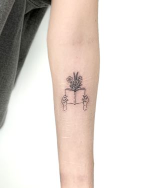 Exquisite fine line tattoo by Bradley Mollett featuring a beautiful flower entwined with a book, perfect for book lovers.