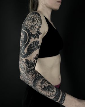 Experience the intricate beauty of a blackwork tattoo featuring a snake and chrysanthemum, expertly done by Lukey Wolf.