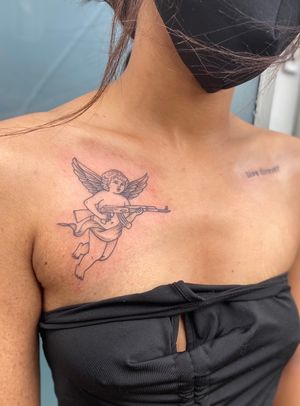 Julia Bertholdi expertly combines fine line and illustrative styles to create a darkly serene tattoo featuring a gun and angel motif.