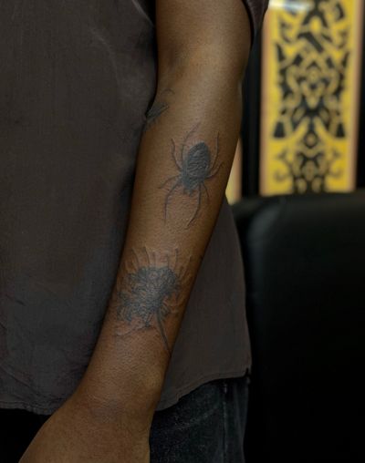 Get mesmerized by this intricately designed blackwork tattoo featuring a spider and spider lily on dark skin. Expertly done by Julia Bertholdi.