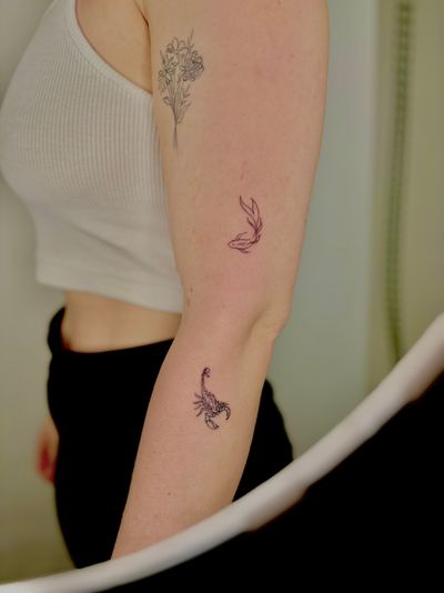 Discover the intricate beauty of Ruth Hall's fine line illustrative tattoo featuring a scorpion and fish motif.