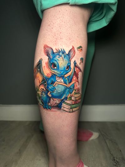 Get a unique and adorable illustrative dragon tattoo in vibrant colors by the talented artist Avi.