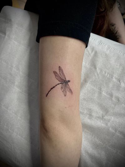 Experience the delicate beauty of fine line and micro-realism in this stunning dragonfly tattoo by the talented artist Nat.