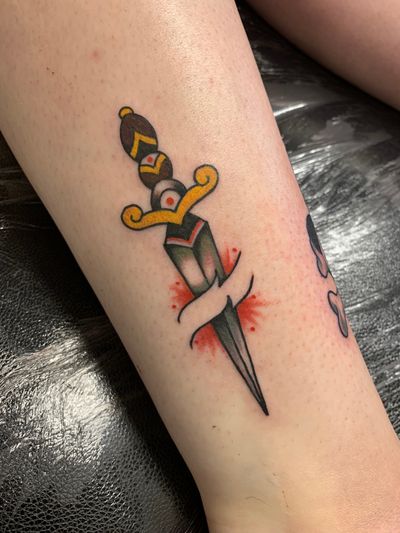 Get inked with a traditional dagger tattoo done by the talented artist Laurel. Classic design with a modern twist!