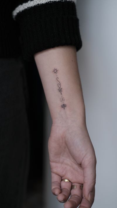 Elegantly hand-poked fine line tattoo featuring a lotus flower and unalome symbol, done by the talented artist Anna.