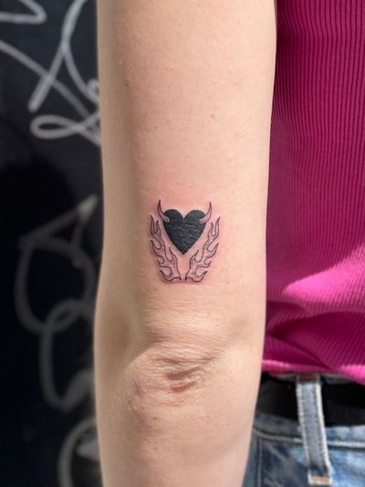 Get inked with this dynamic illustrative tattoo featuring a heart engulfed in flames, skillfully done by artist Julia Bertholdi.