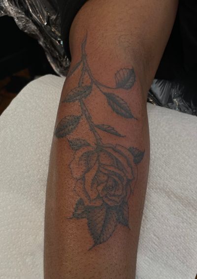 Get a stunning illustrative rose tattoo on dark skin by the talented artist Julia Bertholdi. Embrace the beauty of contrast and intricate details. Book your appointment now!