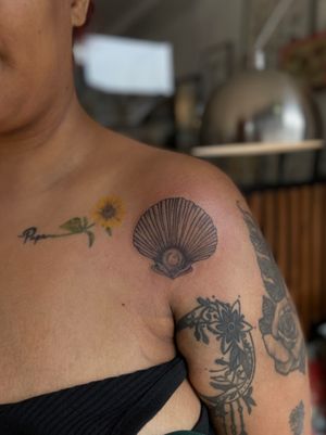 Get inked by Julia Bertholdi with a stunning illustrative tattoo featuring a beautiful shell and pearl motif. Stand out with this unique design!
