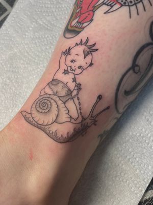 Get whimsical with this illustrative snail and baby tattoo by Julia Bertholdi. A timeless and adorable design for any body art enthusiast.