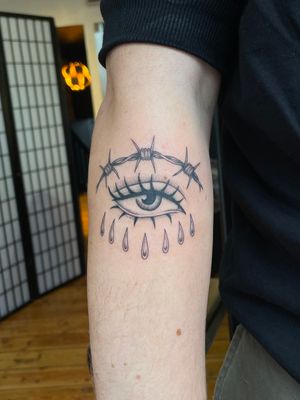 Get a striking illustrative traditional tattoo featuring a barbed wire, eye, and tears design by Julia Bertholdi.