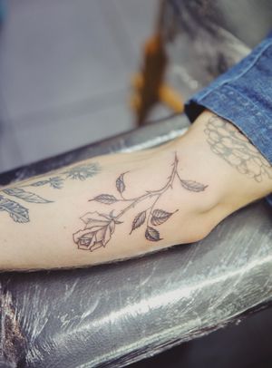 This illustrative tattoo features a stunning black and gray rose, expertly created by renowned artist Julia Bertholdi.