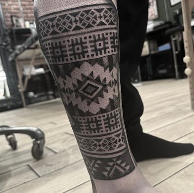 Get a unique tribal tattoo with intricate dotwork patterns inspired by Maori artistry, expertly executed by tattoo artist Sam Waiting.