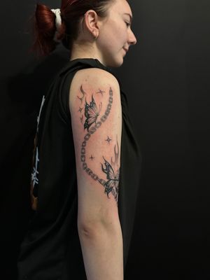 Beautiful tattoo by Oliver Soames featuring a butterfly connected with a chain, combining elegance and symbolism.
