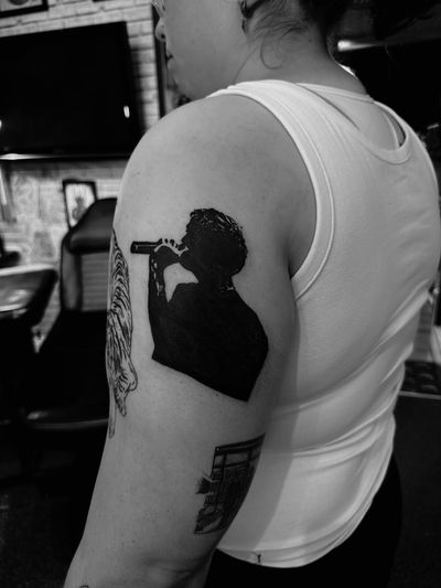 Capture the soulful essence of music with this stunning blackwork tattoo featuring a singer's silhouette, by talented artist Oliver Soames.