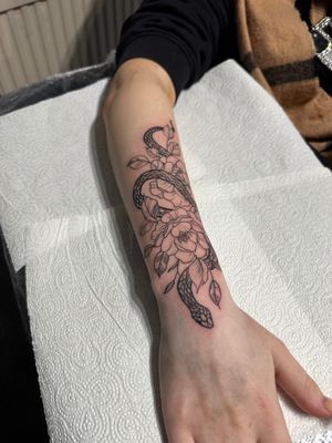 A stunning tattoo combining a snake and flower in a unique illustrative style by the talented artist Oliver Soames.