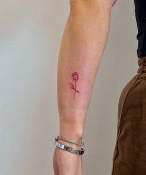Experience the elegance of a fine line rose tattoo in vibrant red ink, expertly crafted by the talented artist Oliver Soames.