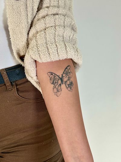 Elegant blackwork and fine line design featuring a butterfly and flower, created by Saka Tattoo.
