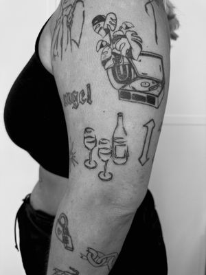 Illustrative tattoo of a bottle and glass, expertly done by Oliver Soames for a unique and stylish look.