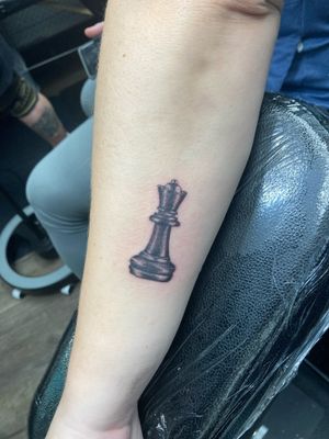 Immerse yourself in the intricate world of chess with this stunning black and gray micro realism tattoo of a queen piece, created by the talented artist Ronny East.