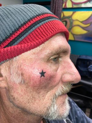 Get a stunning illustrative black star face tattoo by the talented artist Ronny East.