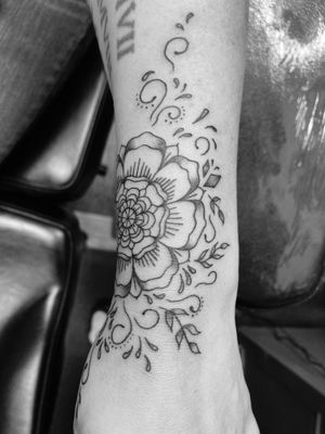 Beautifully detailed tattoo of a tudor rose intertwined with a delicate flower, created by the talented artist Ronny East.