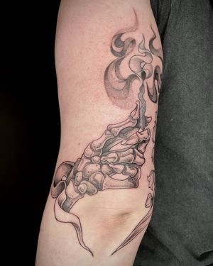 Unique tattoo design by Kat Jennings featuring a detailed skeleton hand holding a matchstick.