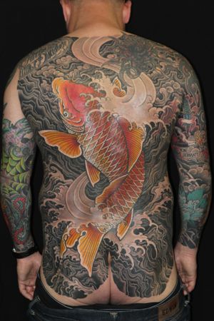 Get mesmerized by this stunning Japanese tattoo featuring a fierce koi fish and powerful waves, expertly crafted by renowned artist Stewart Robson.