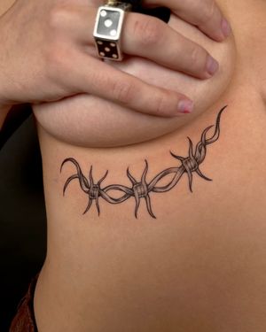 Get edgy with this unique illustrative barbed wire tattoo by the talented artist Kat Jennings. Stand out from the crowd with this bold design.