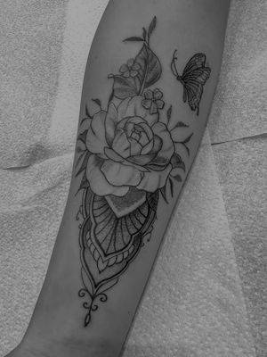 Experience the delicate beauty of ornamental and illustrative style tattoo featuring a butterfly and flower design, created by the talented artist Oliver Soames.