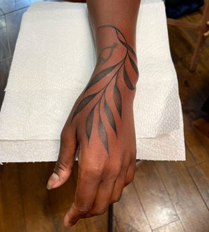 A striking blackwork tattoo featuring a beautifully intricate vine design, by the talented artist Giada Knox, perfect for dark skin tones.