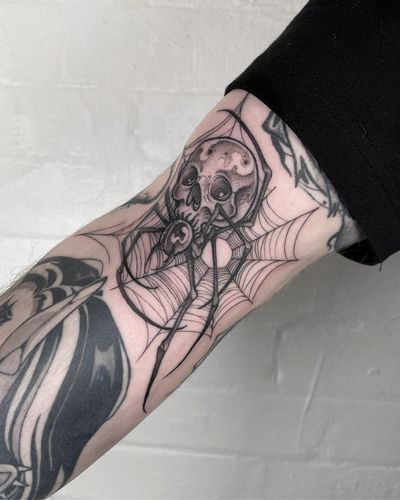 Get a dark and detailed blackwork tattoo featuring a spider and skull, expertly crafted by artist Claudia Smith.