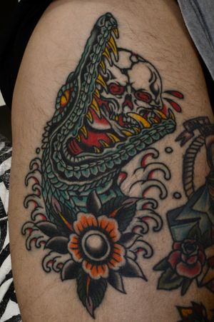 Get a fierce and bold traditional crocodile or alligator tattoo by talented artist Liam Harbison. Perfect for those seeking a powerful and striking design.