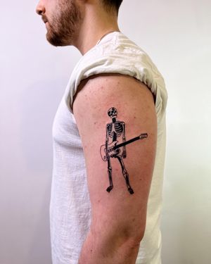 Get inked with a unique blackwork tattoo featuring a skeleton musician playing a guitar, by the talented artist Dave Norman.