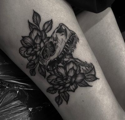 Illustrative tattoo by Sophia Hayes combining a delicate flower with a fierce dinosaur motif.