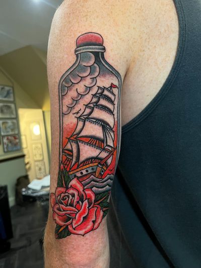 Immerse yourself in the sea with this intricate design by Barney Coles, featuring a ship, rose, and message in a bottle motif. Perfect for traditional tattoo lovers.