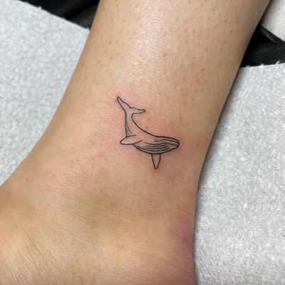 Embrace the beauty of the ocean with this delicate fine line whale tattoo by Chris Harvey.