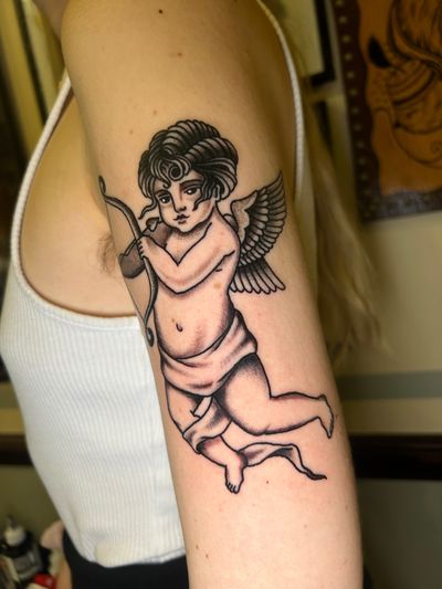 Get inked with this traditional tattoo featuring an angelic cupid design, expertly done by renowned artist Barney Coles.