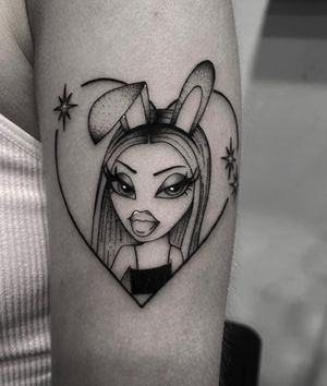 Express your love for unique dolls with this vibrant illustrative tattoo featuring a heart and bratz motif by the talented artist Sophia Hayes.