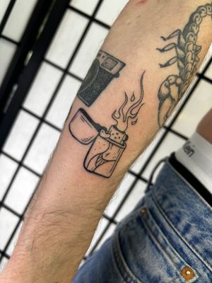 Get a unique illustrative tattoo of a lighter or zippo designed by talented artist Jonathan Glick. Stand out with this cool and detailed piece!