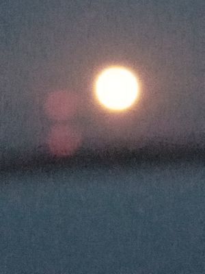Full moon beside a light tower -