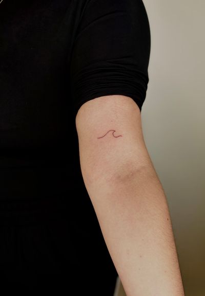 Admire the beauty of a minimal and delicate wave tattoo created with fine line technique by tattoo artist Ruth Hall.