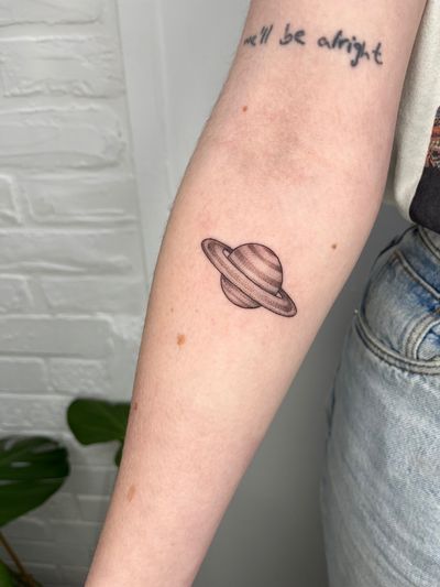 Illustrative black and gray tattoo of Saturn done by Michelle Harrison, showcasing the beauty of the planet with intricate details.