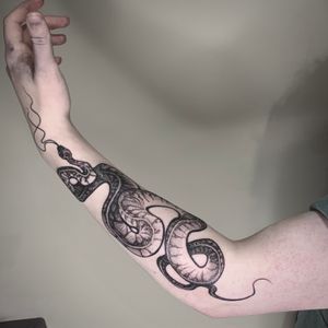 Custom dark illustrative snake on the forearm
