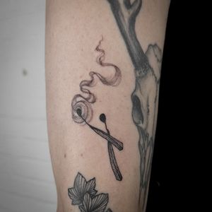 Unique tattoo of a match igniting with smoke, created by talented artist Jenny Dubet. Perfect for those seeking a one-of-a-kind design.